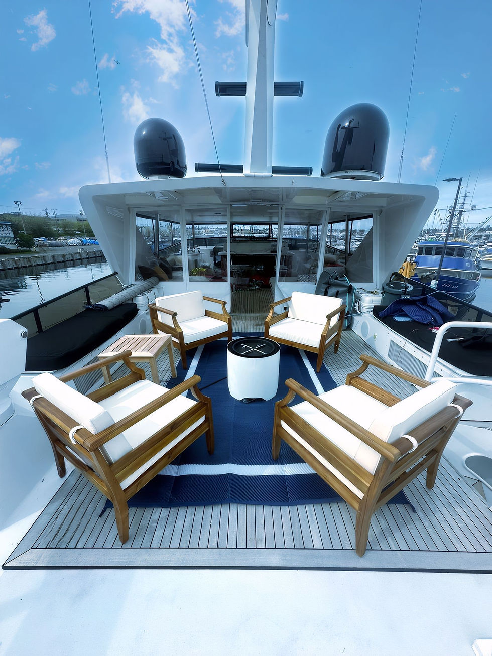 Flybridge lounge on Blackwood with plush seating and a modern speaker fireplace, offering stunning views for relaxation.