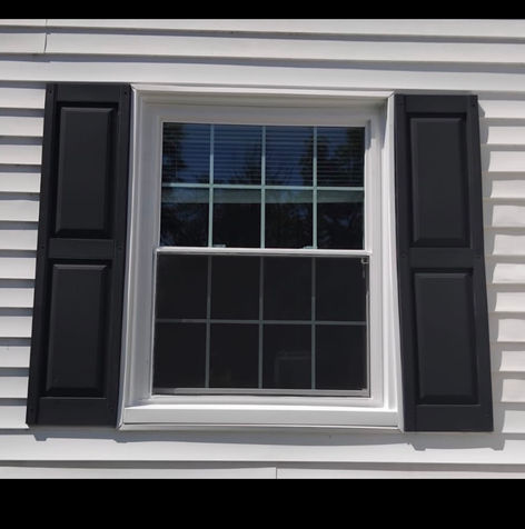 White-framed window with black shutters and white siding