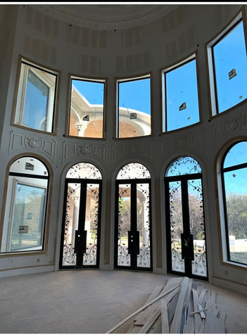 Tall picture windows above decorative arched glass doors in a room under renovation