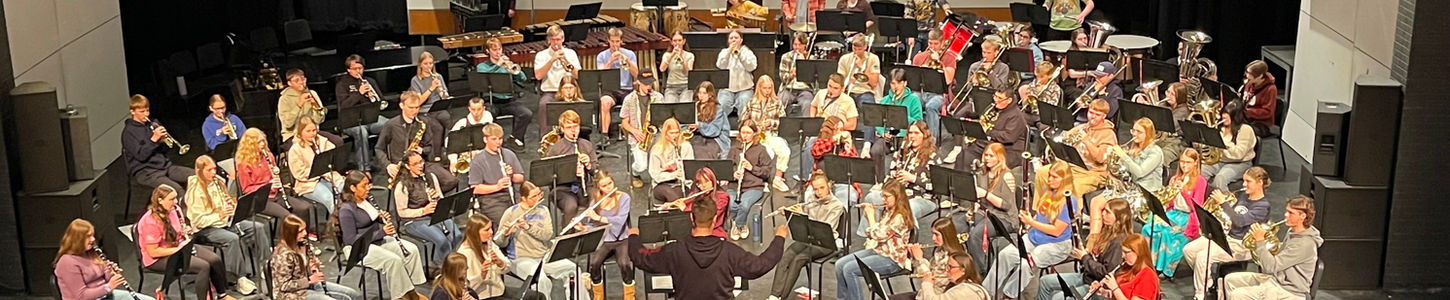Conductor leading Crookston Secondary School band on stage