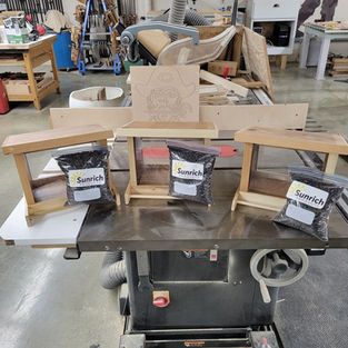 Three small wooden benches and bags of wood shavings in a workshop