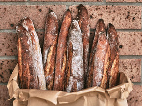a paper bag filled with sourdough baguettes.
