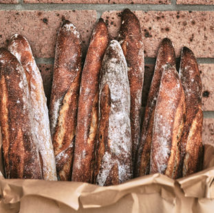a paper bag filled with sourdough baguettes.