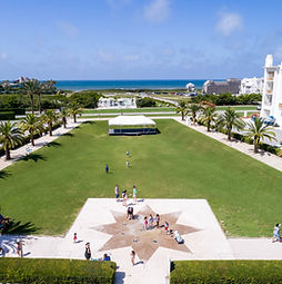 Families playing by the splash pad at Alys Beach Florida with white buildings and palm trees near the Gulf on 30A