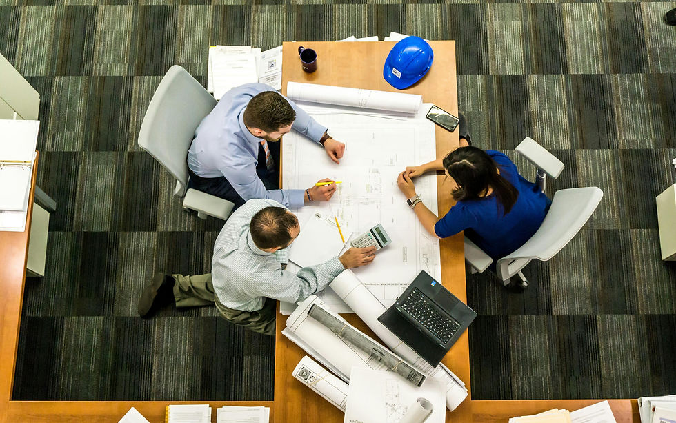 Overhead view of architects reviewing blueprints with a laptop and hard hat.