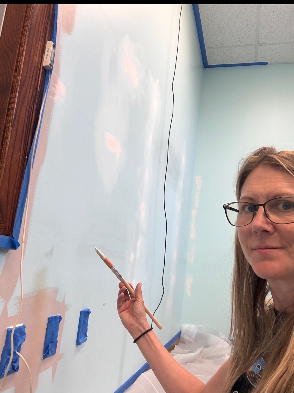 Chelsea working on a wall painting project at the Endcap, adding a fresh layer of color to the space.