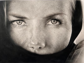 Monochrome depiction of a female face with expressive eyes, looking into the camera.