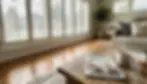 White vinyl plantation shutters on a living room window filtering soft daylight — an affordable option for cheapest plantation shutters.