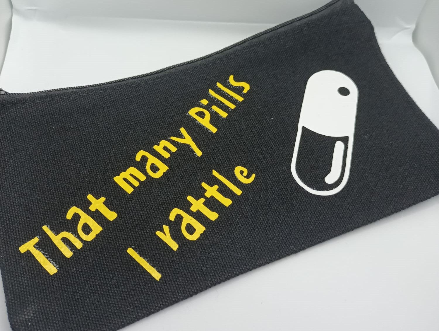 Black zip pouch with yellow writing that many pills I rattle