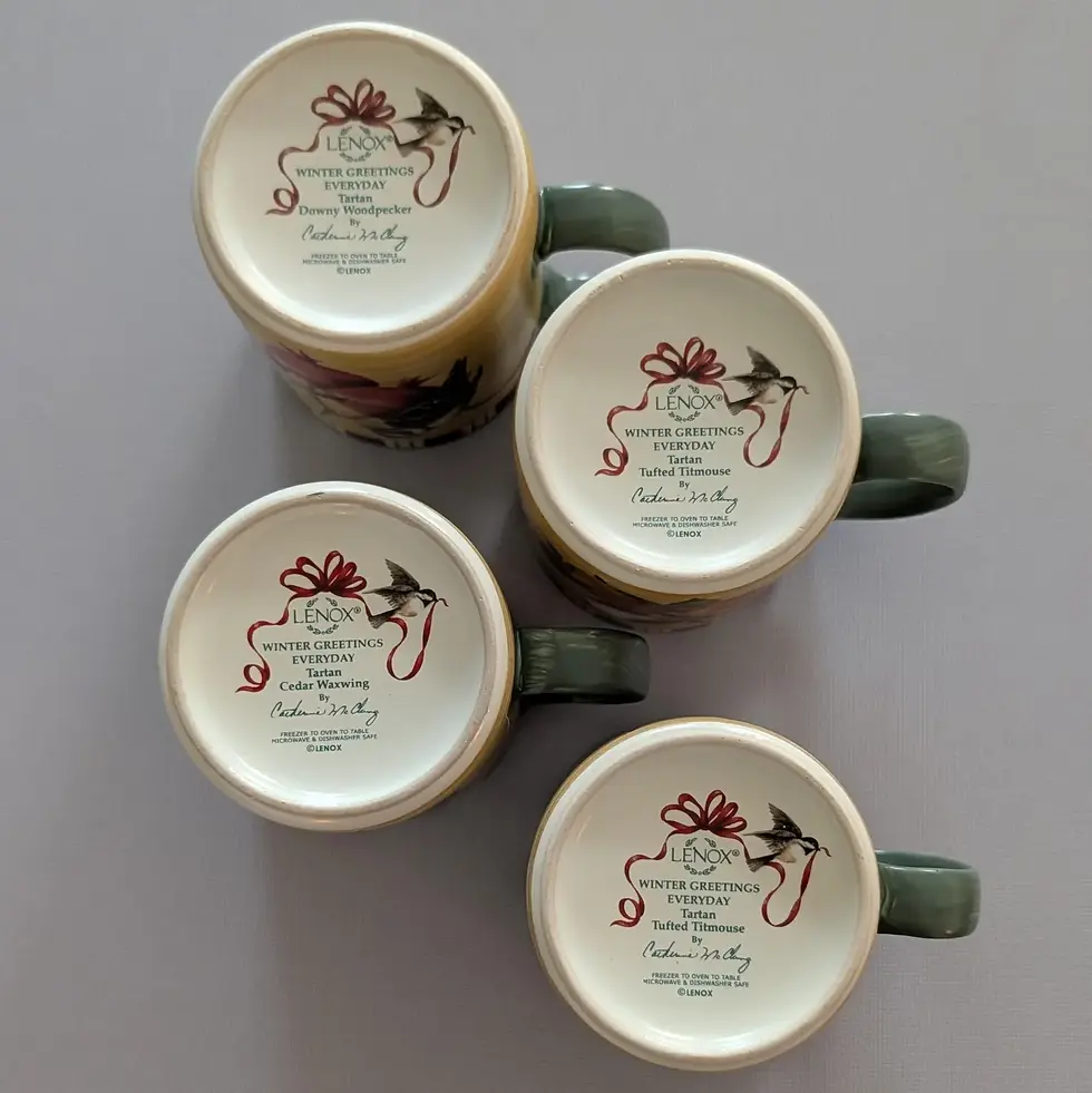 Thumbnail: bottom of stoneware mugs that says winter greetings everyday by lenox catherine mcclung with a red ribbon and a bird