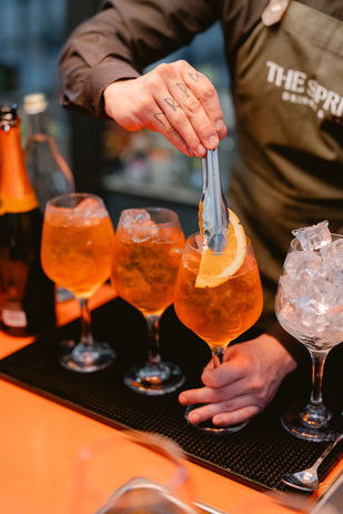Aperol Spritz clásico servido en copa elegante con rodaja de naranja y hielo, preparado como parte de la experiencia de coctelería premium para eventos sociales y corporativos.