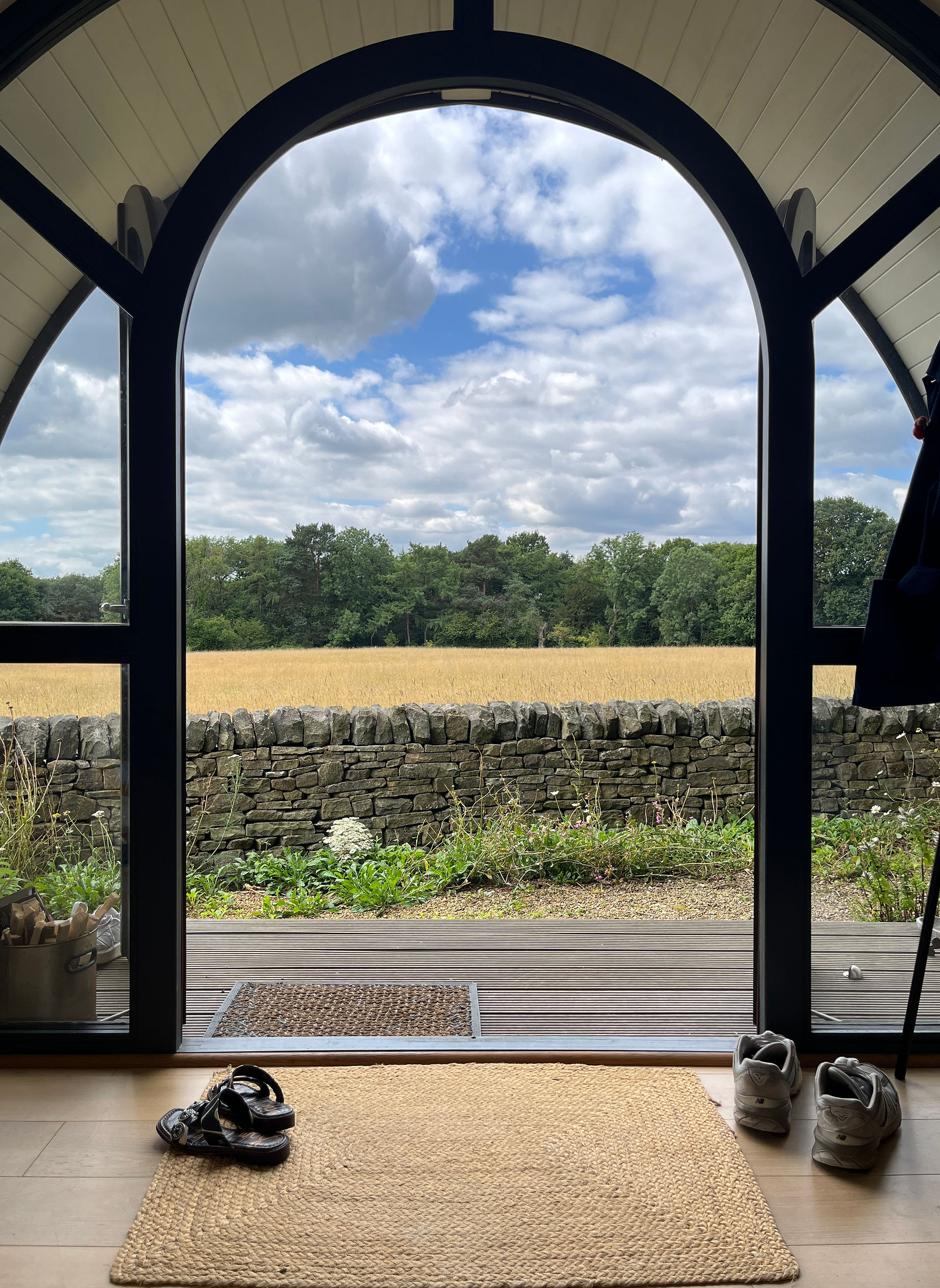 View through the arched doorway of Oak Tree Pod, looking out over the meadow