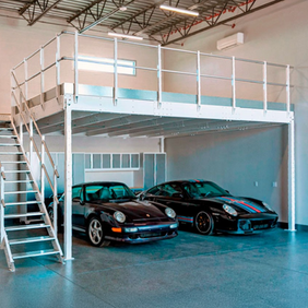 En utställningshall med ett entresolplan med två fina sportbilar under.