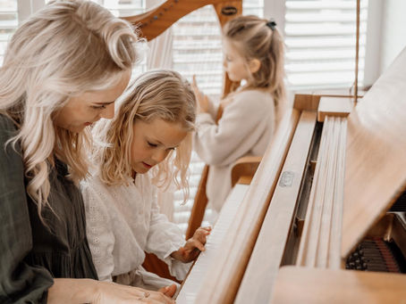 An au pair teaches two children piano.