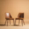 Two same size empty chairs facing each other, thin mid century modern chairs, against a li...und.jpg