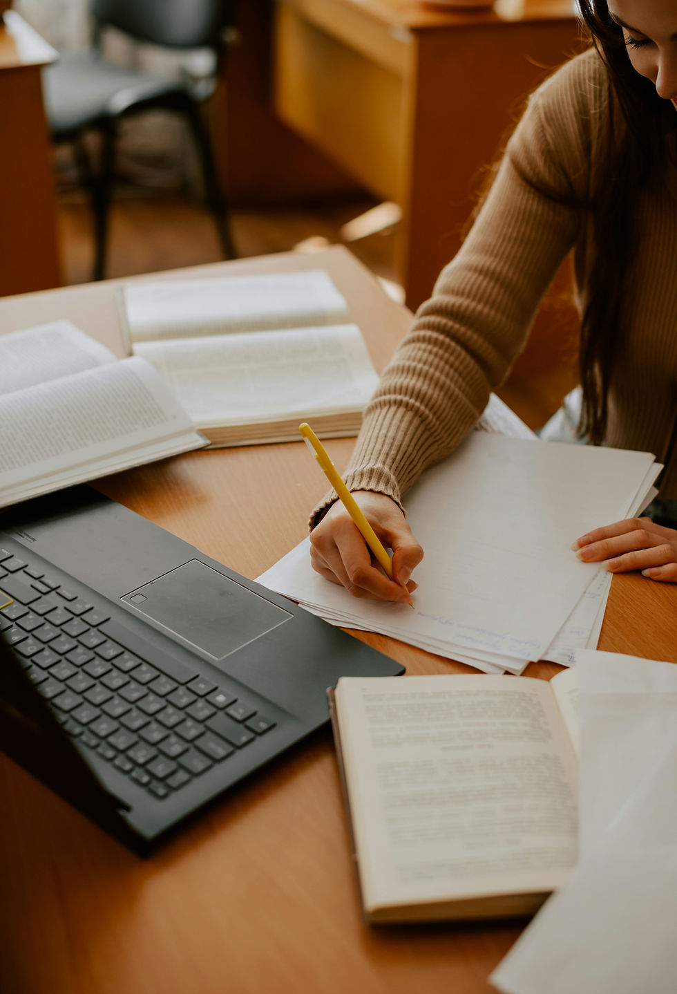 Person studying clinical caregiving materials at a desk with books, notebook, and laptop
