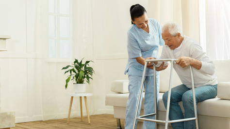 Caregiver helping a person with dementia walk safely at home, demonstrating fall prevention strategies.