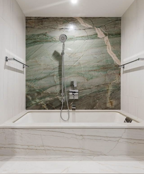 bathtub with green marble accent wall