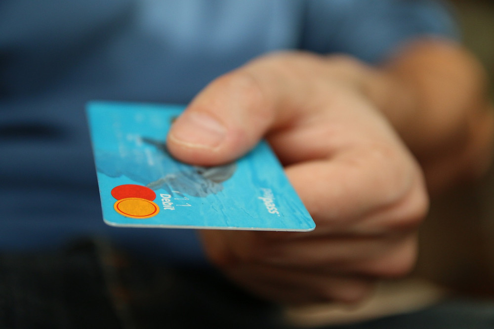 Close up shot of a hand holding out a blue debit card