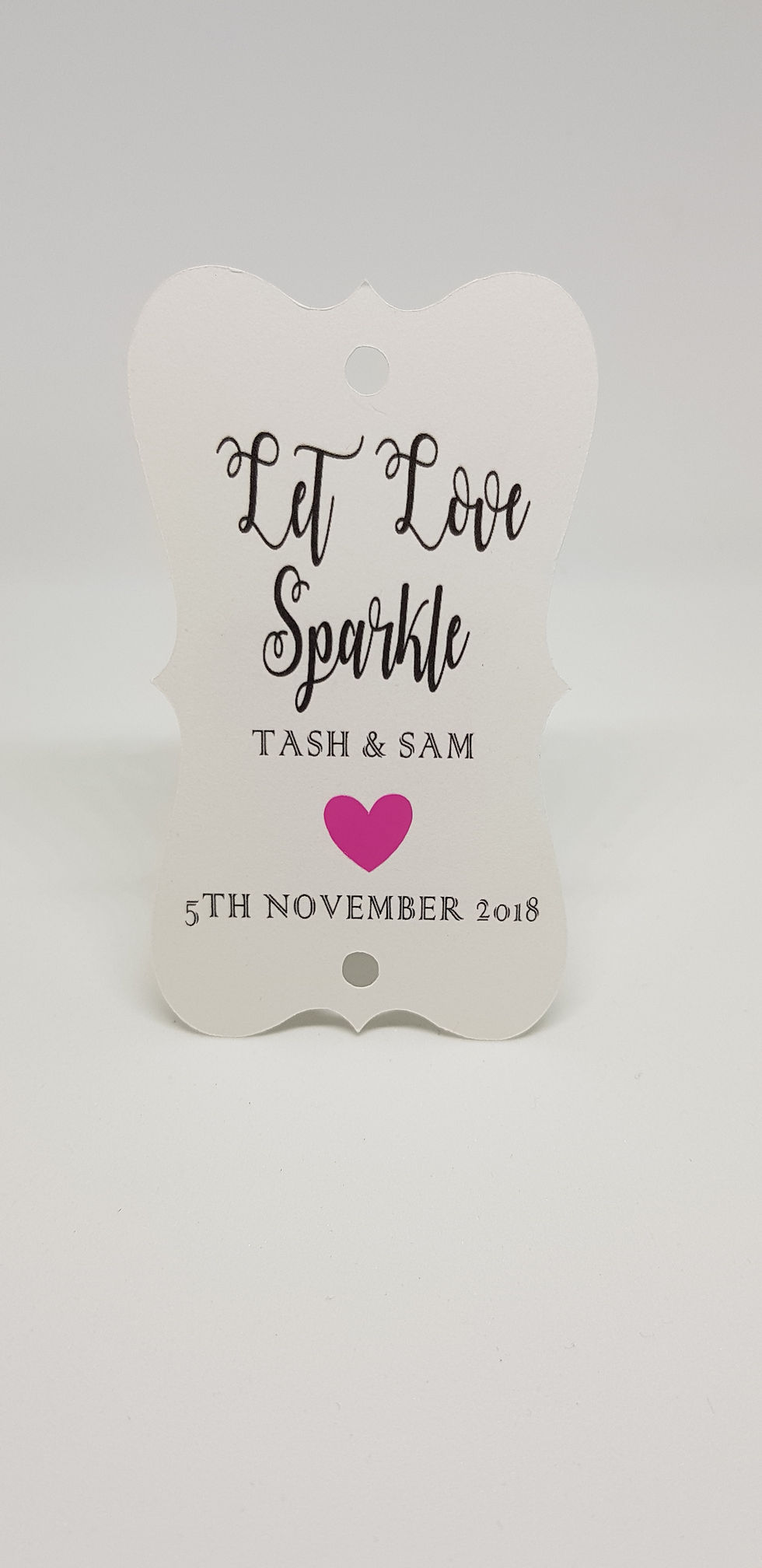 Thumbnail: Let love sparkle Tag with a pink (bright) heart. The heart is in between your names and wedding date.