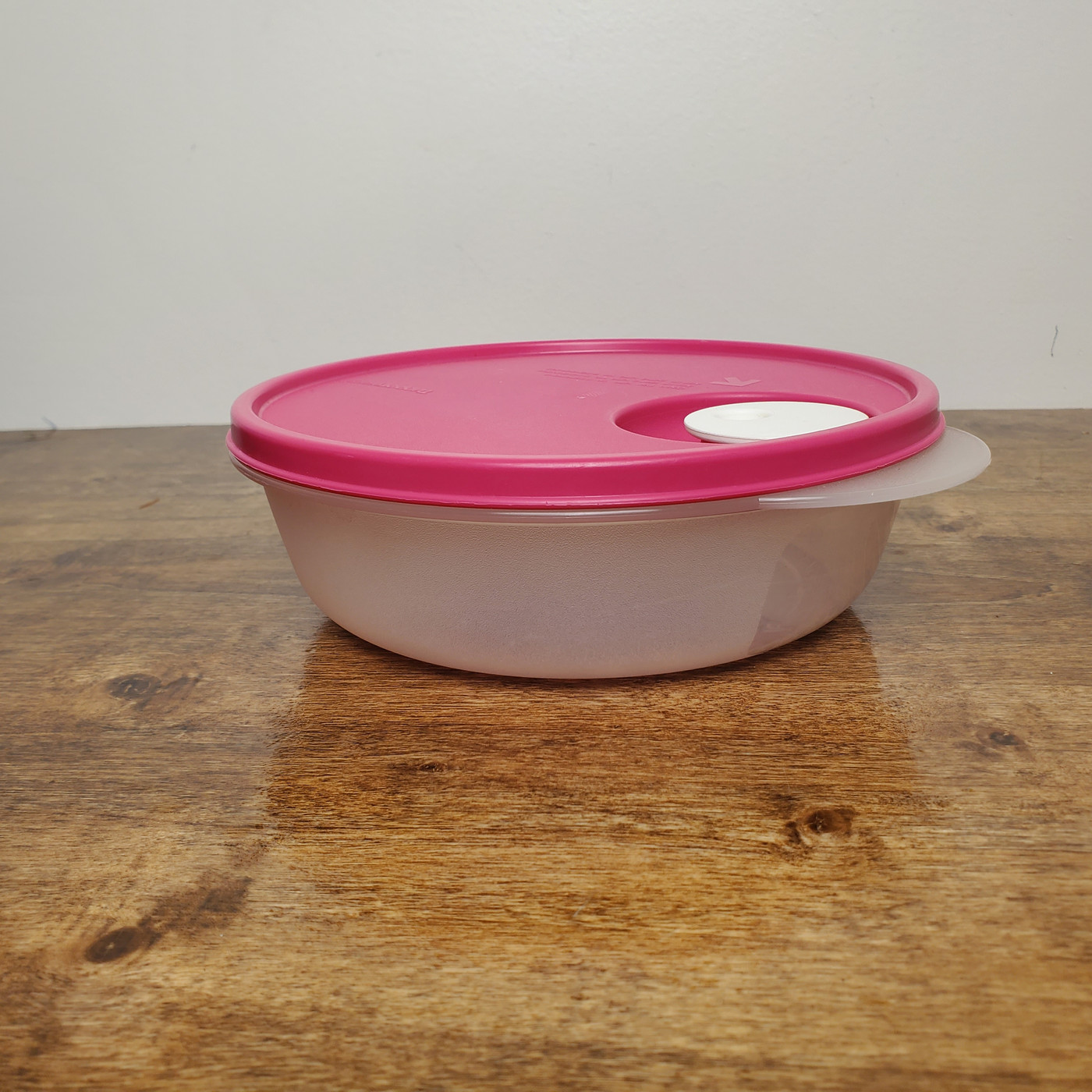 Tupperware CrystalWave round bowl with vibrant pink vented lid.