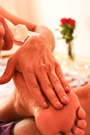 Fußmassage mit Lotion, Rosen im Hintergrund
