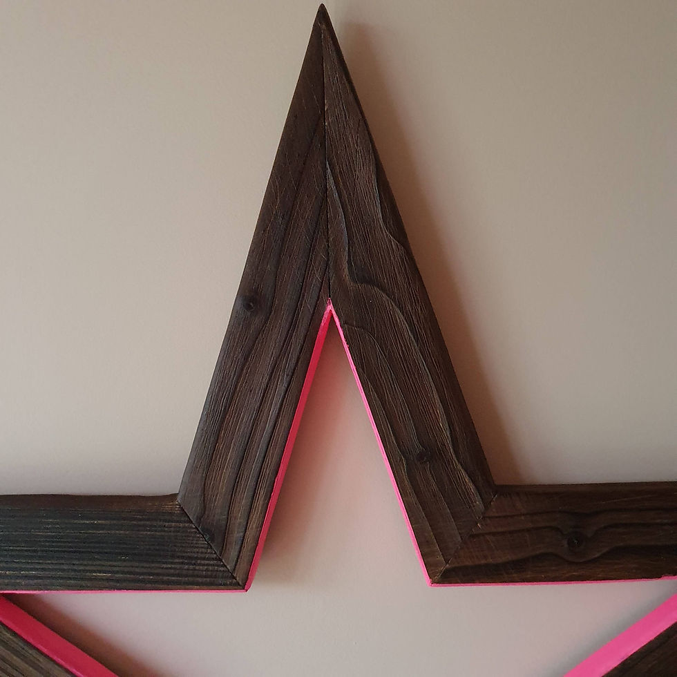 Thumbnail: Charred wooden star painted with neon pink on pink wall close up