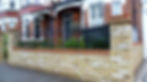 yellow brick london garden wall with metal wrought iron rail and formal planting hedge
