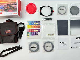 Kit Kase K100 Wolverine sobre fundo branco, com estojo, suporte, filtros cinza, manual e caixa com foto de pôr do sol.