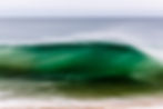 Fotografia de onda verde em movimento próximo à praia.
