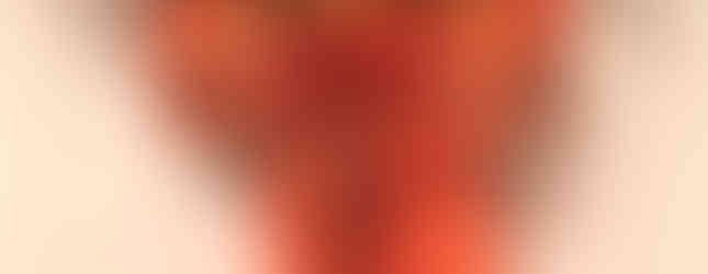 A basket filled with little pumpkins with a large orange bow with long tails hung by an orange plaid ribbon.