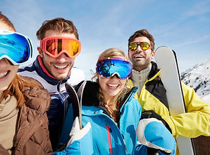 Friends carrying skis on mountain top
