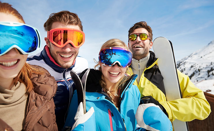 Friends carrying skis on mountain top