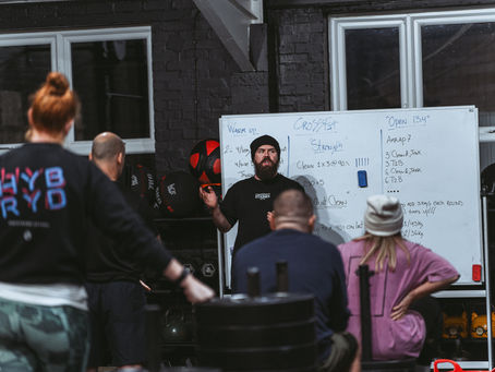 CrossFit Staines coach demonstrating proper lifting technique during a workout session, offering personalized guidance to gym members