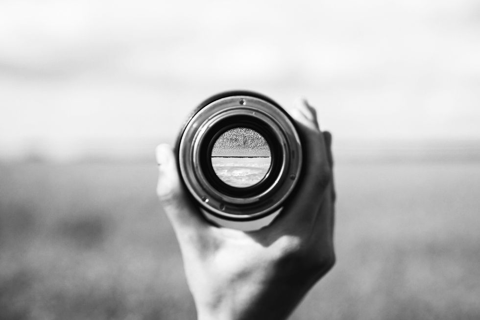 Hands holding a camera lens focused on the shoreline, representing clear social media strategy for wellness brands.
