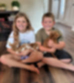Children holding Goldendoodle puppies during early socialization, helping raise confident, family-friendly puppies in a home-based breeding environment