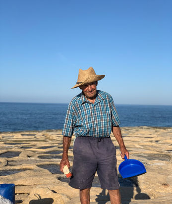 Our sea salt harvester stands with simple tools at the ancient salt pan ready to give a sea salt harvesting demonstration during the sea salt harvesting tour