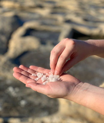A tourist holds the coarse sea salt crystals in her hand during the sea salt harvesting tour