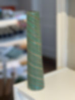 Tall straight green vase with stripes swirling around the pottery