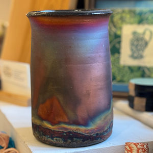 patterned large pot with glossy black rim at the top on a white shelf
