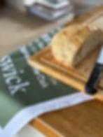 Tea towel under a chopping board with bread and knife