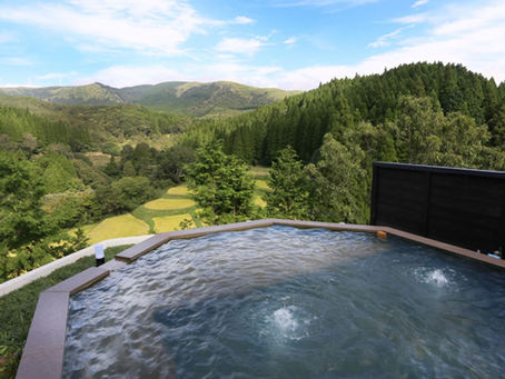 Banho termal a céu aberto com vista para as montanhas e florestas de Kyushu, em Kurokawa Onsen, cercado por natureza e silêncio.