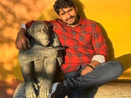 man sitting next to statue of monkey