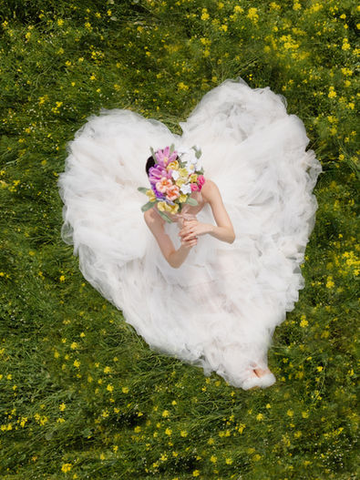 koil filmの前撮り写真 — 白い羽根とお花で作ったハート型の中に座る花嫁のスナップ