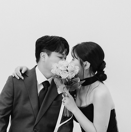 koil filmのフォト&ムービープラン撮影写真 — 白いバラの花束越しに寄り添う新郎新婦のモノクロスナップ