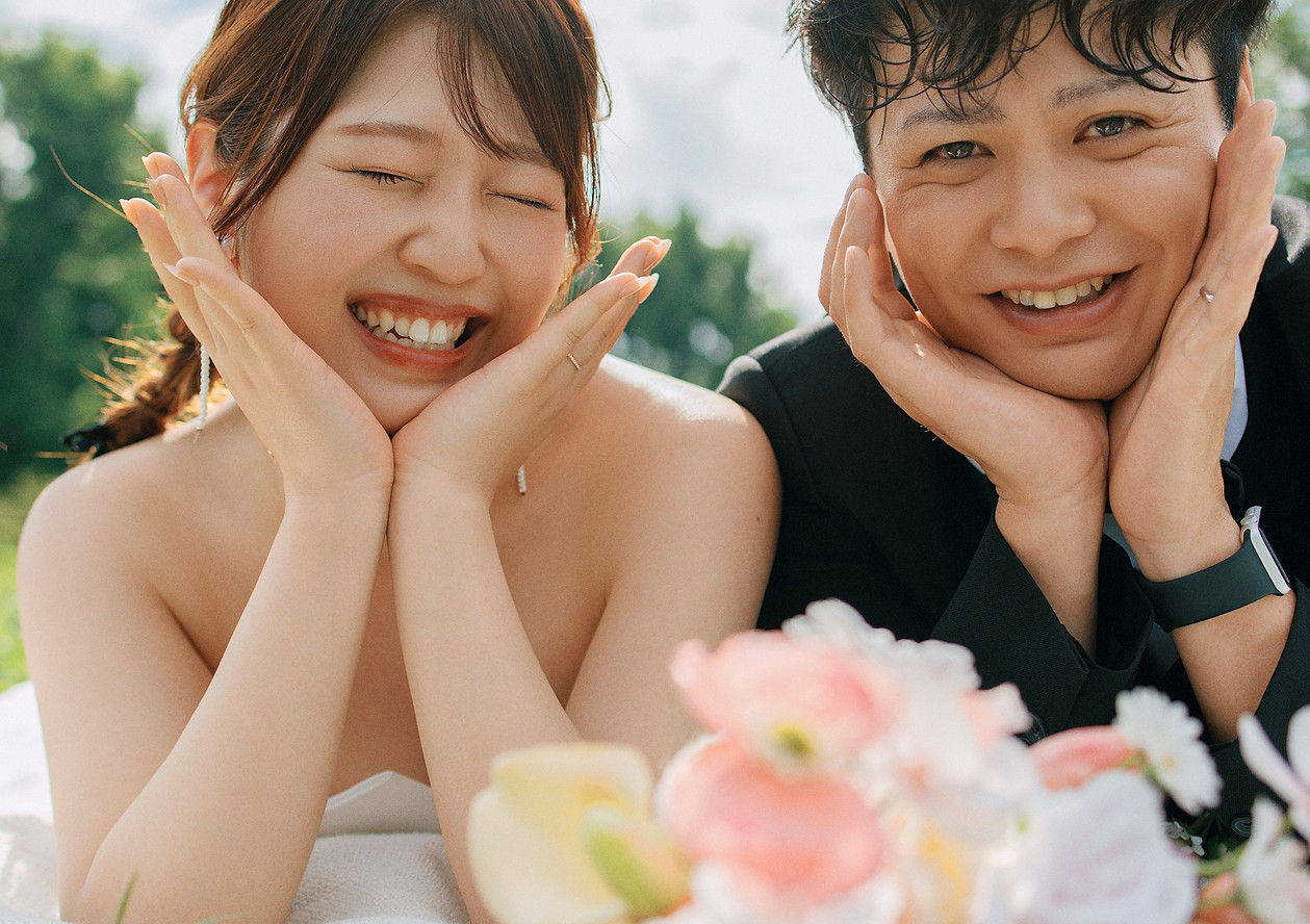 koil filmの前撮り写真 — うつ伏せで肘を付いて微笑み合う新郎新婦のスナップ