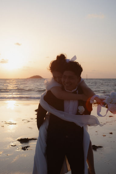 角島の海辺で新婦をおんぶして笑い合う新郎新婦