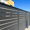 Modern metal fence for fencing the yard area. Horizontal sections of the fence made of met