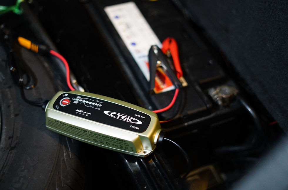Sports car in storage with battery maintainer connected to prevent battery drain.