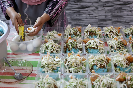 A Muslim female adult is preparing 'nasi kerabu' packed lunch (blue pea steamed rice with side vegetable dishes accompanied with fried chicken and chilli sauce) at home. She is a home-based chef and accommodate orders during Ramadan season coincide with partial lockdown in Malaysia.